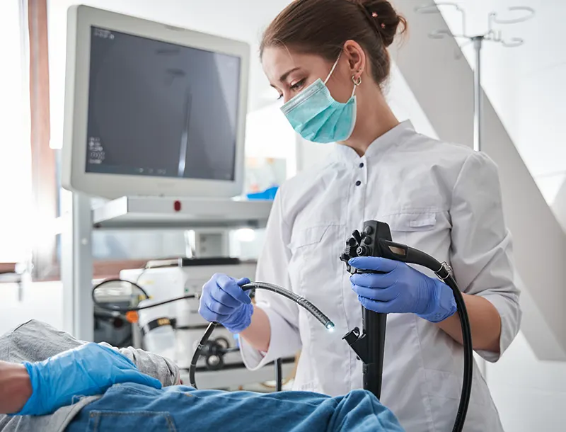 Female doctor wearing protective mask holding endoscope during gastroscopy